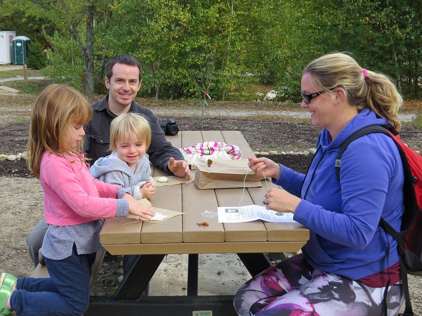 family working on a project outdoors on a picnic table