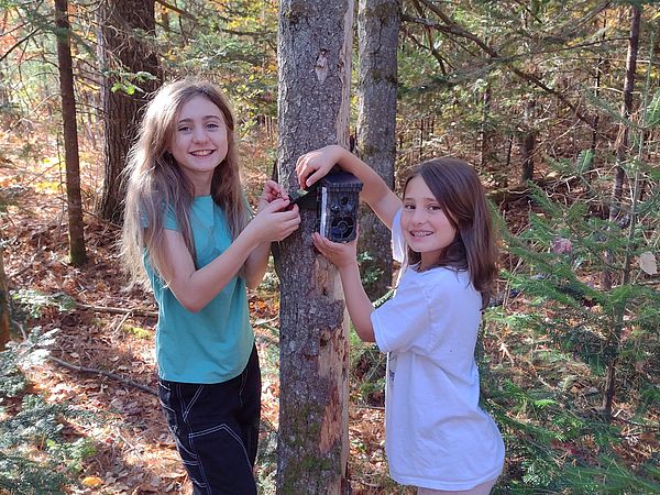 Students hang a camera in the forest.