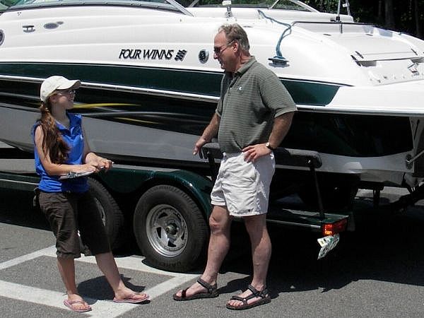 Two people talking in front of a boat, one person is holding a clipboard