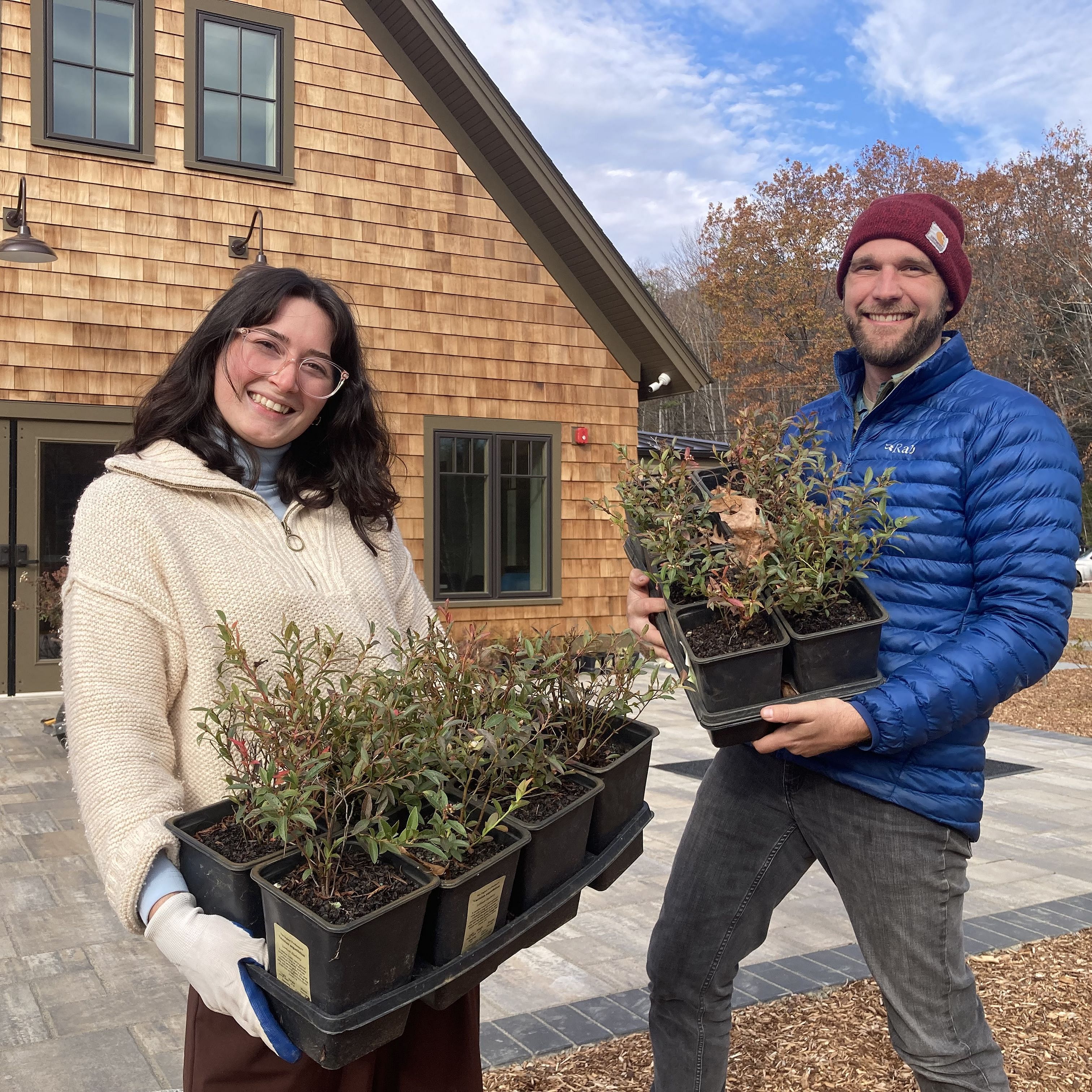 NLRA staff holding trays of native plants.