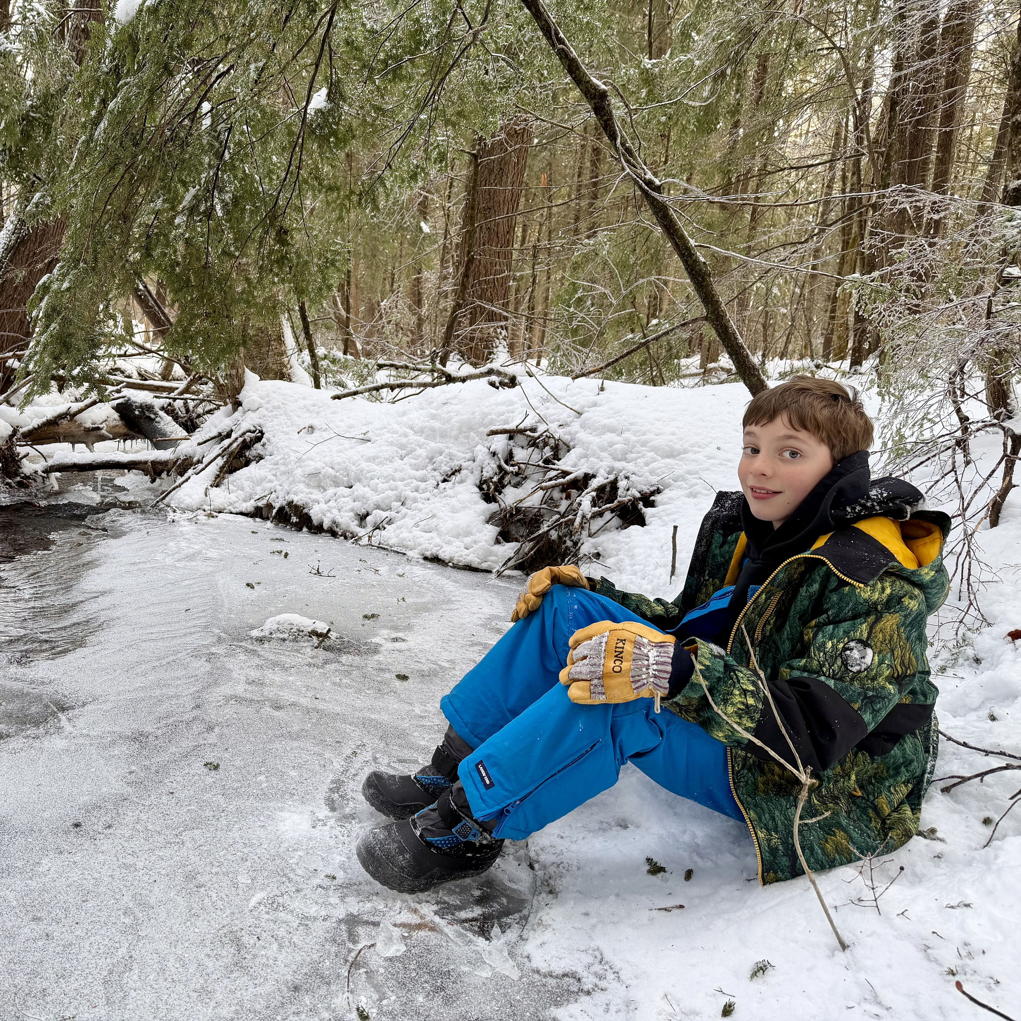 Smiling child at the edge of a frozen stream in winter.