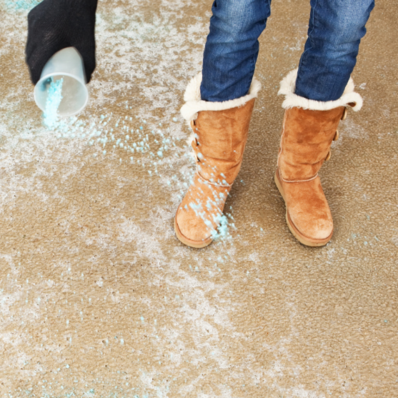 Person spreads ice melt across driveway.
