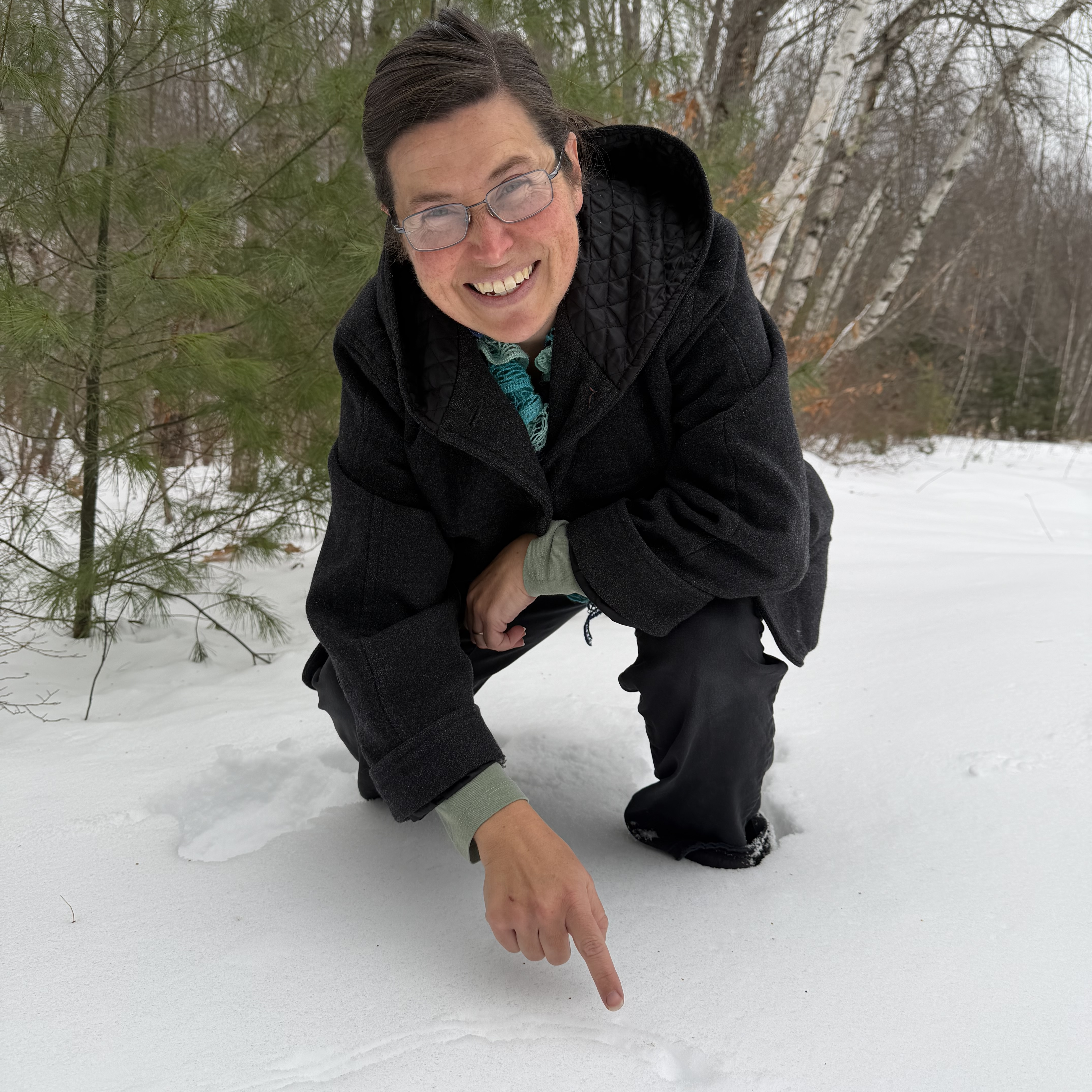 A naturalist pointing out rodent tracks in the snow.